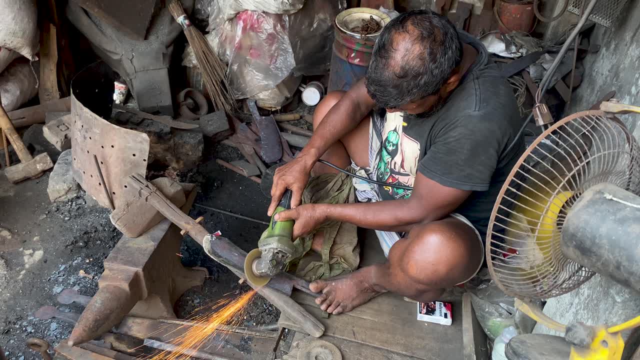 Blacksmith Man polishing iron knife with angle grinder at his shop in Bangladesh