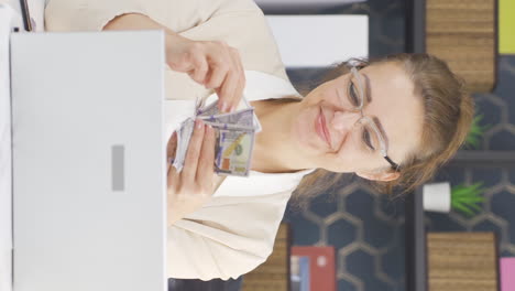 Vertical-video-of-Business-woman-counting-money-looking-at-camera.