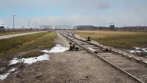 looking down auschwitz concentration camp rail tracks as light snowflakes fall