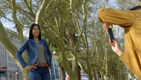 Young-mixed-race-man-clicking-photo-of-woman-with-mobile-phone-in-the-city-4k