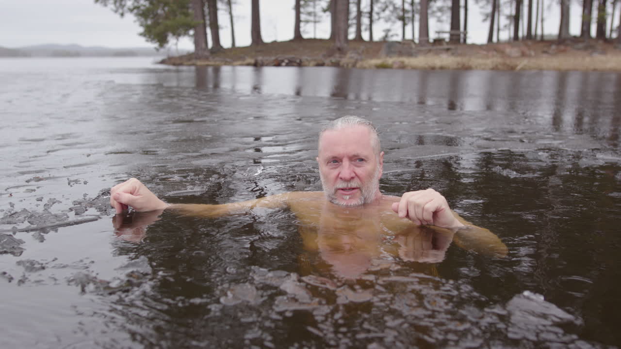 un hombre bañándose en el hielo en sus últimos 50 años disfruta de la serenidad de la exposición al frío, la lluvia