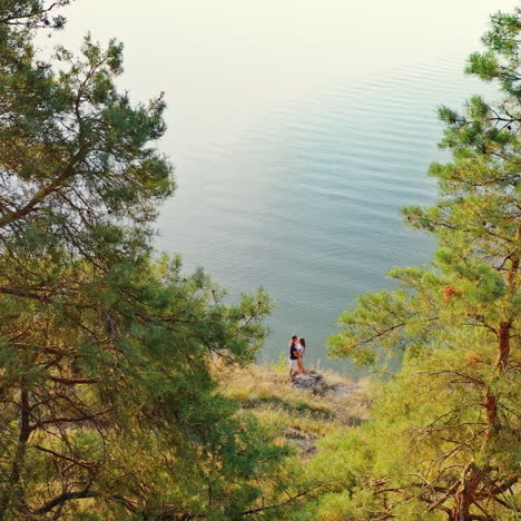 romantic couple hugging at the sea shore. natural landscape of the sunny summer day and young man and a girl kiss each other. aerial view.
