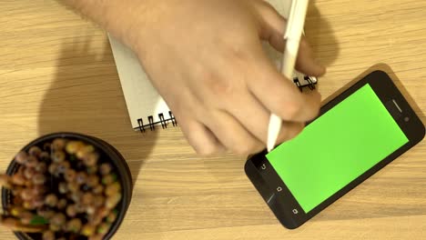 internet en un teléfono móvil. el especialista está sentado en el escritorio. pantalla verde.