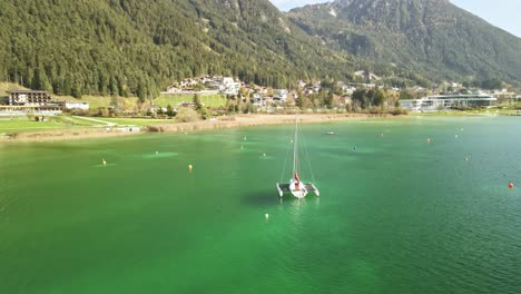 a mesmerizing drone shot at achensee on a sunny summer day, flying around a boat gliding over vibrant turquoise water, capturing the tranquil beauty of austria's largest alpine lake.