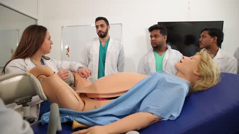 vertical shot of senior male professor of medicine compressing manikins chest demonstrating cpr technique on training model while teaching students first aid in practical class at university