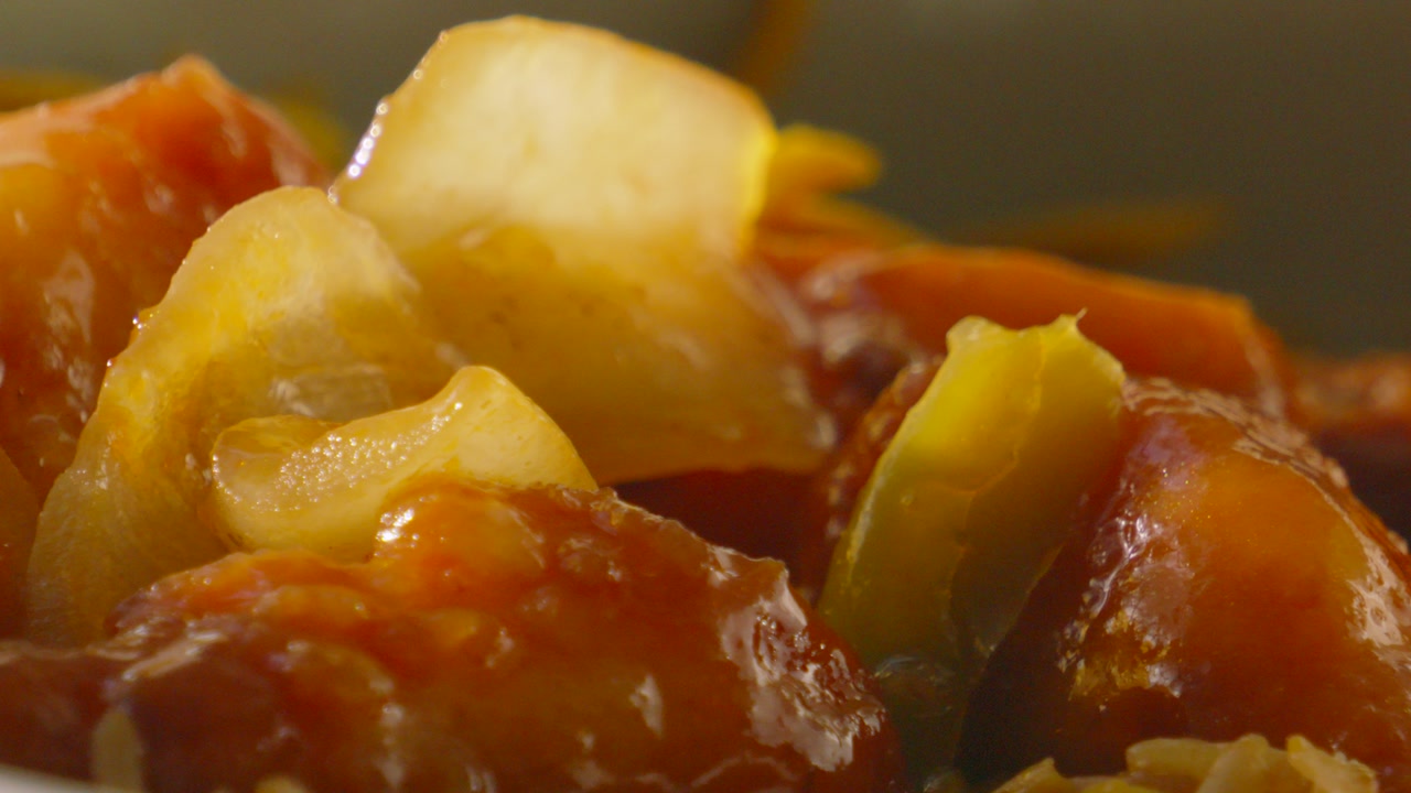 Delicious Sweet and Sour Chicken with Large Onions in Natural Sunlight as Camera Moves Slowly Across. Tasty Oriental Food.