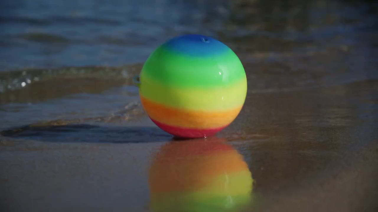 Bola pantai berwarna-warni mengambang di tepi ombak lembut di pantai berpasir Plage de la Gravette di Antibes, Prancis, pada hari musim panas yang cerah di French Riviera.