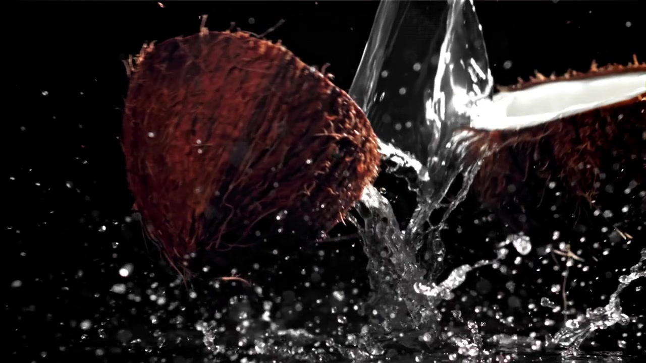 Rottura di cocco al rallentatore e schizzi d'acqua su sfondo nero