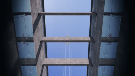 airplane flies over concrete building with glass elements