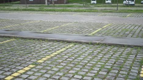 empty parking lot with grass and cobblestones