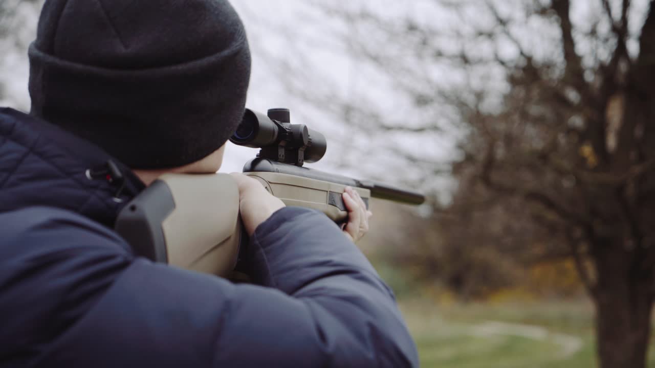 Hunter with gun on forest. Close up of the hunter man shooting with hunting rifle on nature