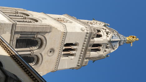 golden statue of virgin mary atop basilica of notre-dame de fourviere bell tower, lyon - vertical video against blue sky