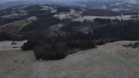 Ein-Flug-über-Die-Landschaft-Mit-Einem-Pfad,-Der-Durch-Die-Bäume-Führt,-Und-Einem-Blick-Auf-Die-Umgebung-Während-Des-Beginnenden-Schneefalls