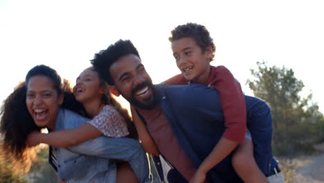 parents giving their kids piggybacks outdoors, waist up