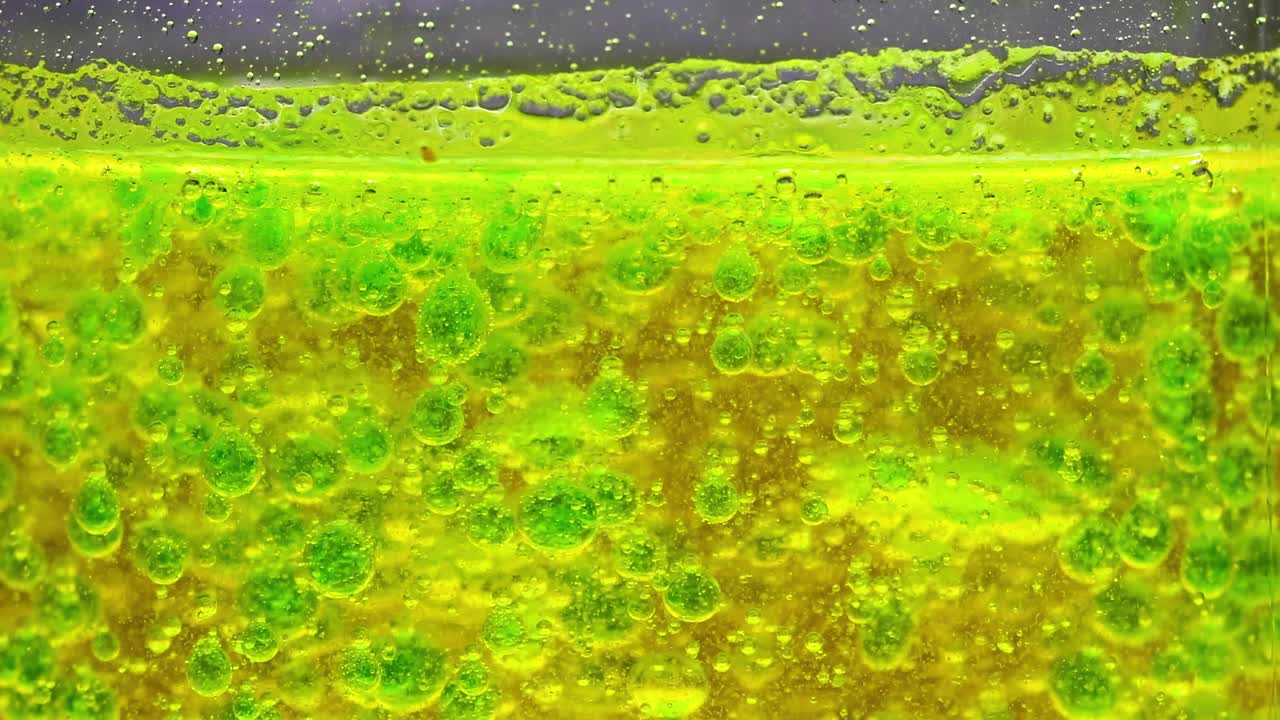 Watch the dynamic interaction of green and yellow bubbles in a liquid environment.