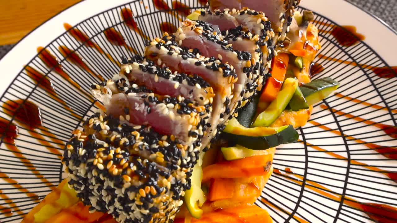 Close up view of tuna tataki with sesame crust, raw center and seared edges, served with sweet potato mash and vegetables at a coastal Portuguese restaurant. Smooth glide over the fancy seafood