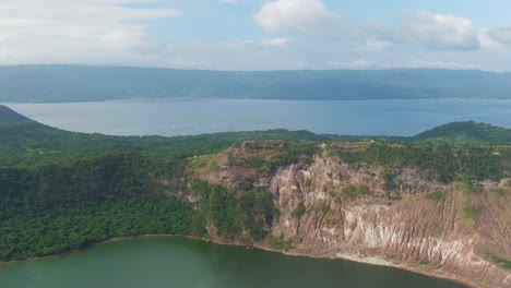 Peaceful-nice-view-from-the-corner-hillside-of-the-crater-lake-at-the-center-on-an-Island-surrounded-by-the-Taal-Lake-and-silhouette-mountains