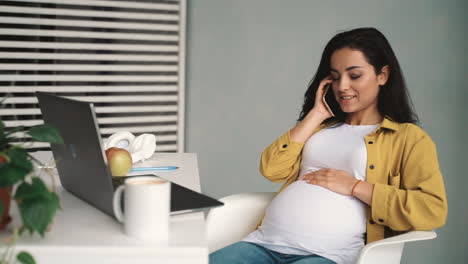 joven feliz embarazada mujer de negocios hablando por teléfono