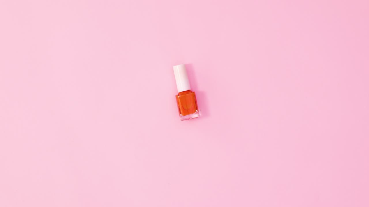 botella de esmalte de uñas de manicura girando sobre un fondo rosa pastel. colocación plana de movimiento de parada