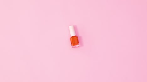 botella de esmalte de uñas de manicura girando sobre un fondo rosa pastel. colocación plana de movimiento de parada