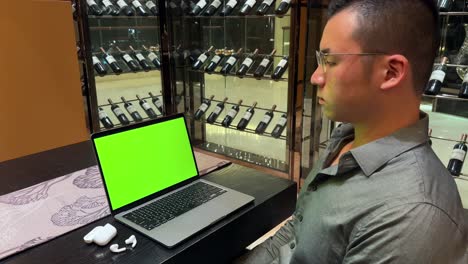 hombre millennial asiático rico mirando una computadora portátil con pantalla verde en una casa de lujo