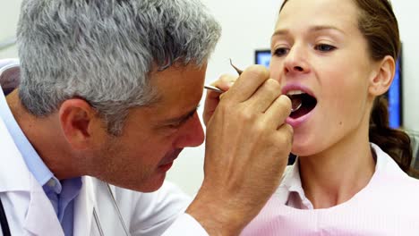 Dentist-examining-a-female-patient-with-tools