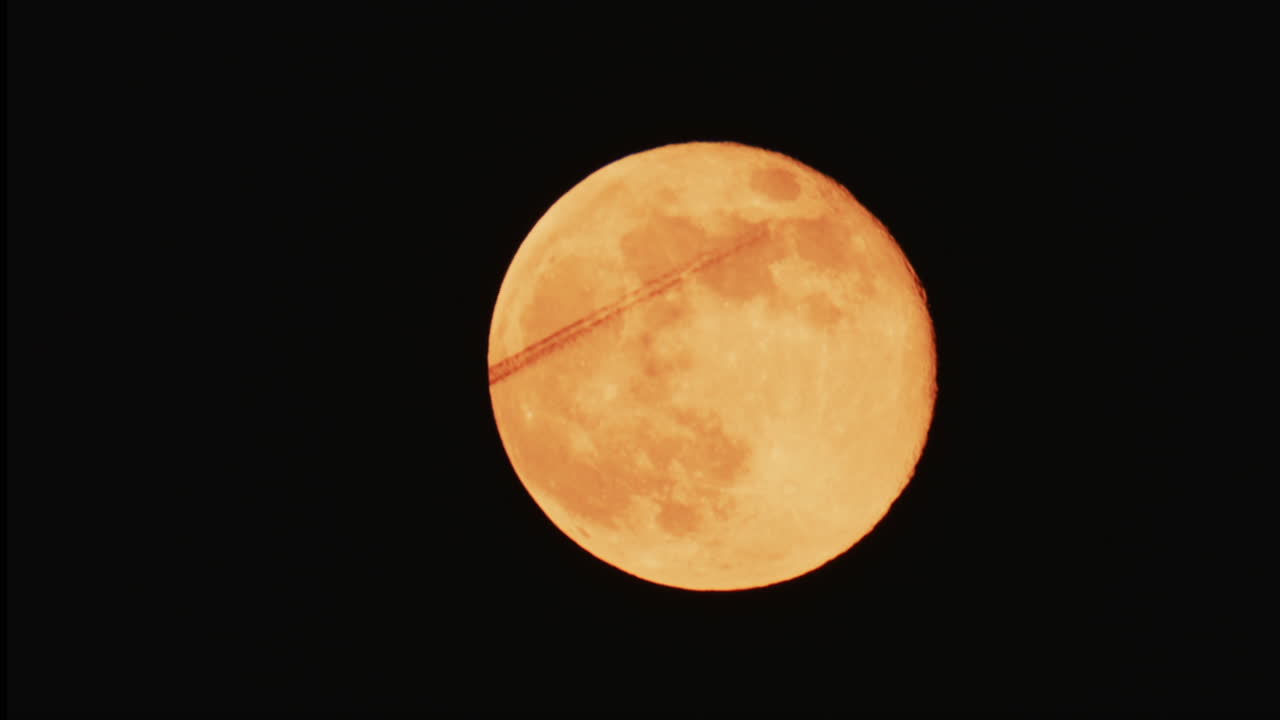 Large full moon rising against a dark night sky with clear details and dramatic atmosphere