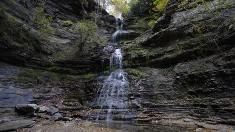 Statische-Aufnahme-Eines-Kleinen-Wasserfalls-Am-Schluchtfluss-Mit-Fallenden-Blättern