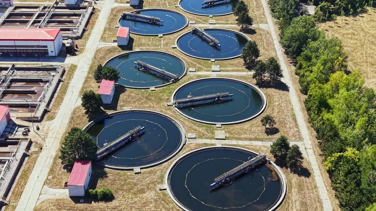 Water treatment facility with circular tanks and green surroundings in bright daylight