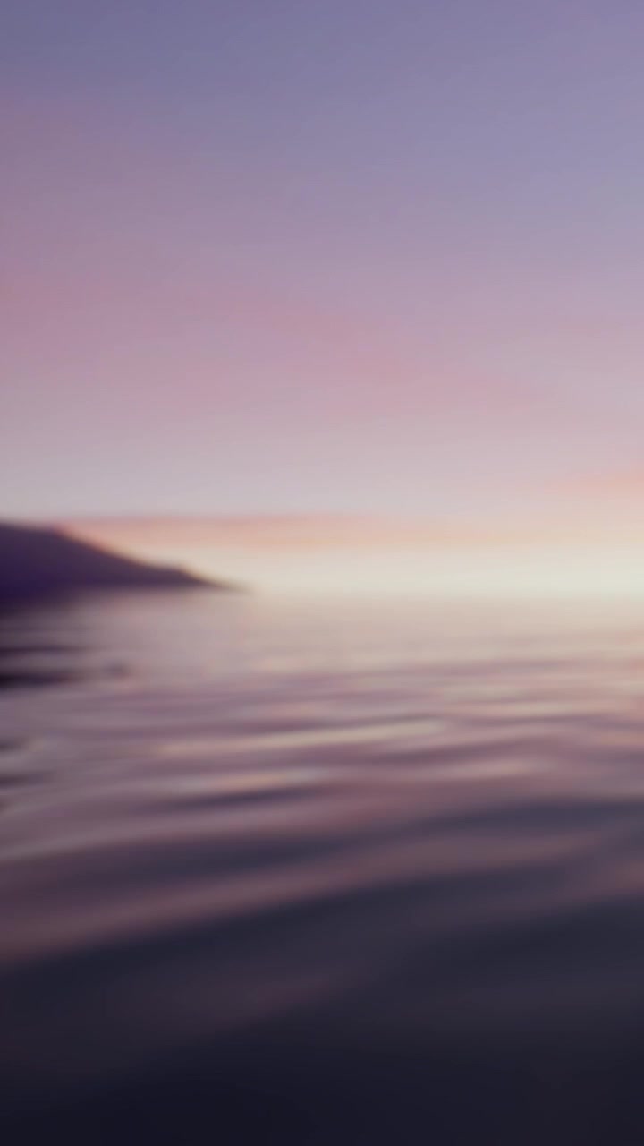 Sunrise over calm lake with soft colors and distant mountains in view