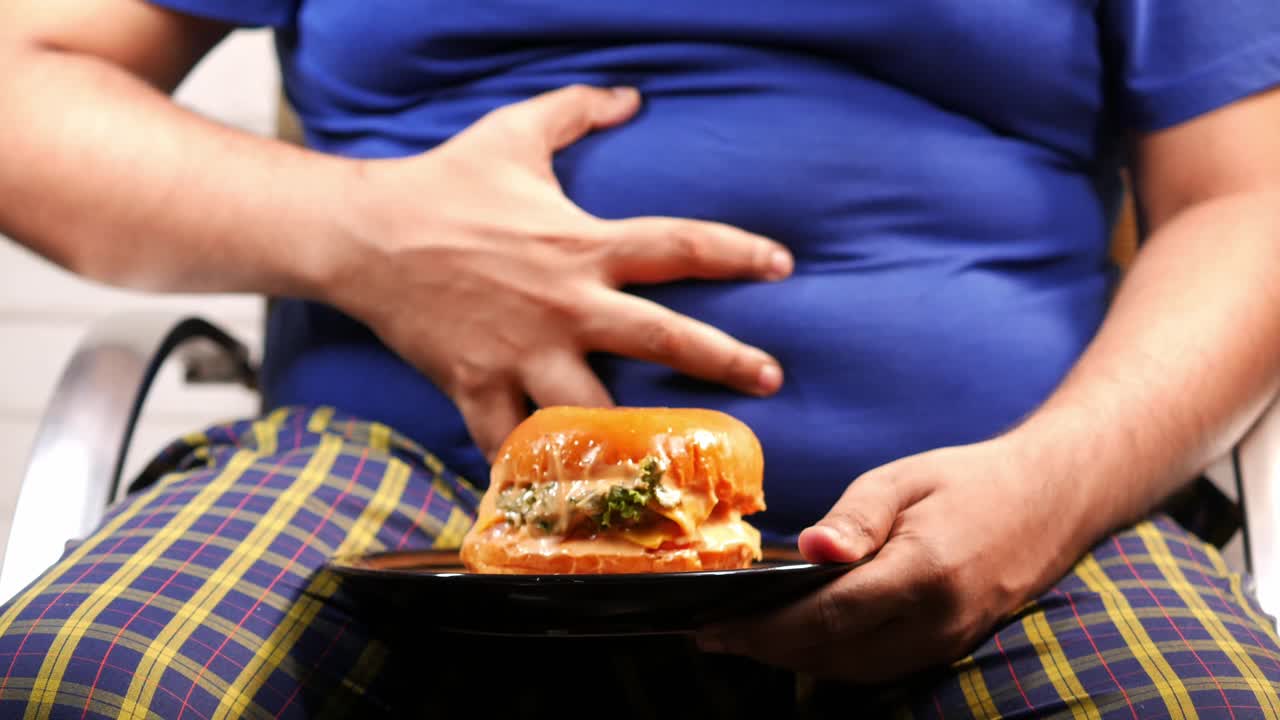 Overweight Man Suffering from Possible Digestive Issues after Eating a Burger