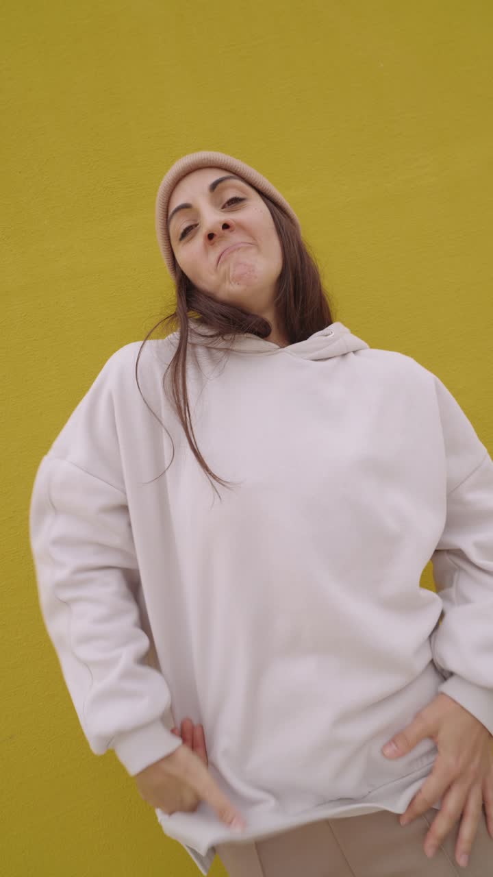 Woman posing in front of yellow wall