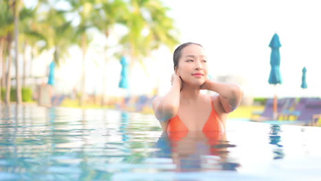 Sexy-Mujer-Asiática-En-Bikini-En-La-Piscina-Acaricia-Su-Cabello-Mojado,-Cámara-Lenta