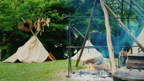 숲 음식에 있는 아메리카 원주민 캠프가 전경 전통 wigwam 텐트에서 준비되고 있습니다.