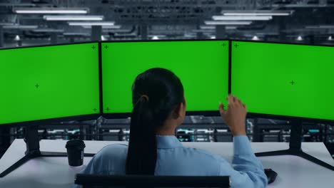 back view of tired asian woman yawning while working with mock up multiple computer monitor in data center