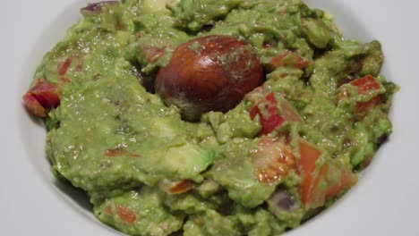 Inclinar-Hacia-Arriba,-Tazón-De-Guacamole-Fresco-Con-Hueso-De-Aguacate,-Primer-Plano