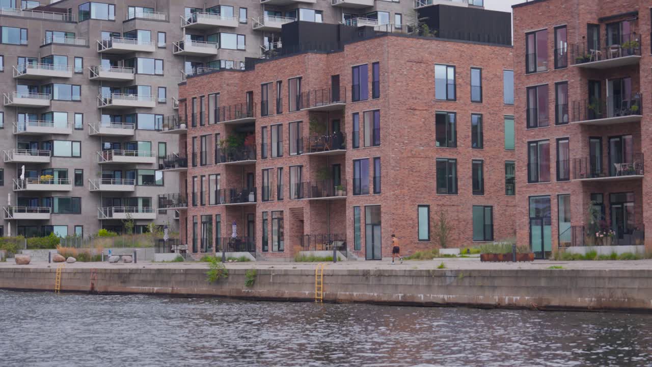 Multistory waterfront buildings, person run on embankment, Copenhagen