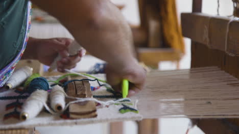 a zapotec woman using a loom to hand weave a tapestry in oaxaca, mexico