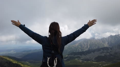 toma cinematográfica de una mujer con los brazos extendidos como señal de libertad y asombrada por el maravilloso paisaje de las montañas tatra en polonia