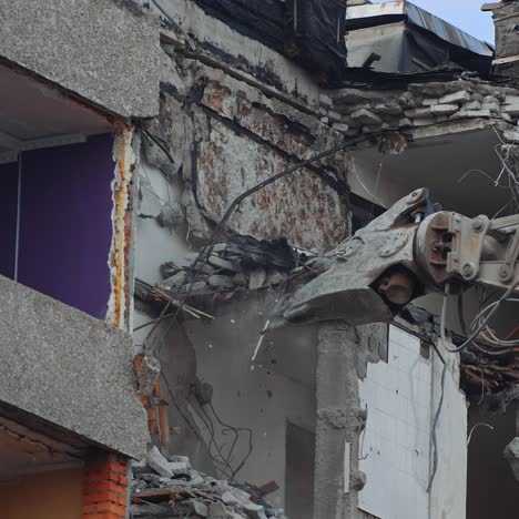 demolition of the house previously destroyed by natural disaster. special machinery breaks the parts of ruins. dusty debris falling down the ground
