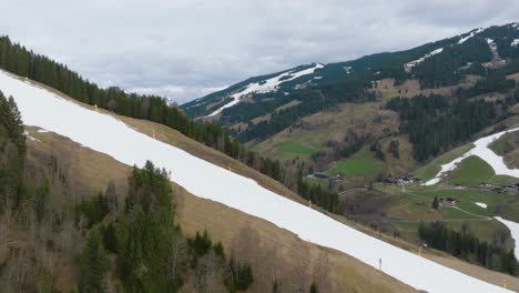 Schmelzender-Schnee-Auf-Den-Hängen-Von-Saalbach-Hinterglemm,-Fleckig-Grün,-Luftaufnahme