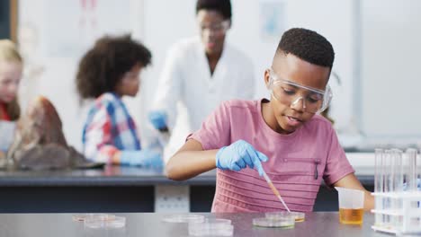 Diverse-female-teacher-and-happy-schoolchildren-having-science-class-in-school-lab