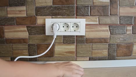 a woman's hand connecting and disconnecting multiple home appliances in to a triple power wall socket