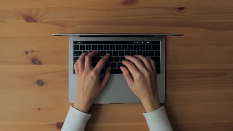 Hände,-Die-Auf-Einem-Laptop-Auf-Einem-Holzschreibtisch-Tippen