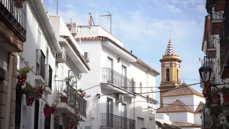 White-city-buildings-and-church-tower-in-Estepona,-panning-view