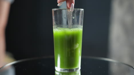 water pouring into glass with green juice creating bubbles and a gentle swirl