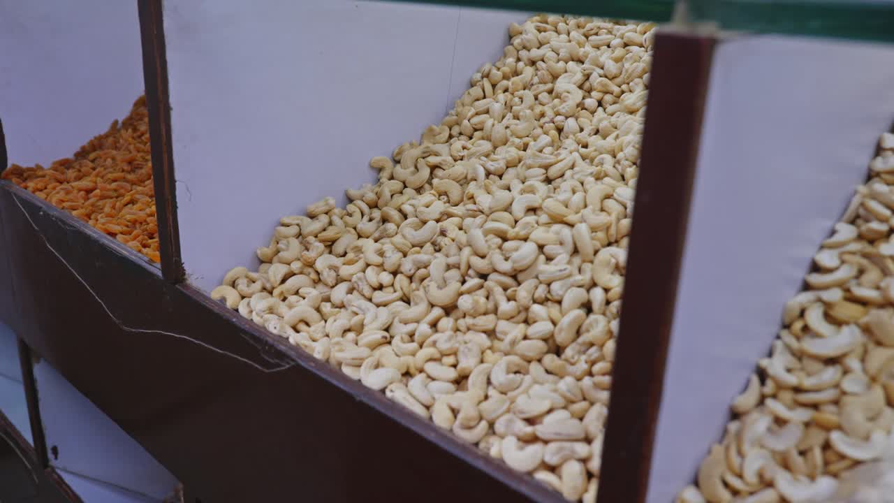 Cashew nuts with raisins are display in wood rack for sell in supermarket or kirana store, india. stable shot, 4k.