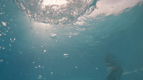 cinematic slow motion shot of air bubbles in clear waters with the sun above the sea surface, 4k, 120fps, slomo