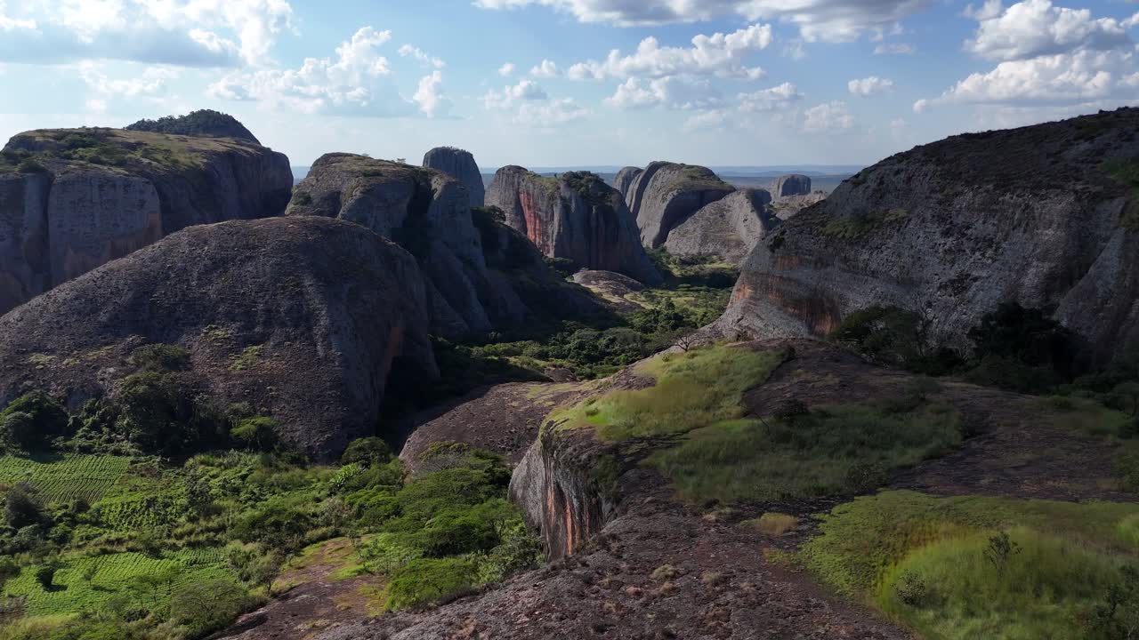 drone footage flying between massive rock pillars of Pedras Negras, Angola, revealing surreal geological shapes and vibrant natural colors