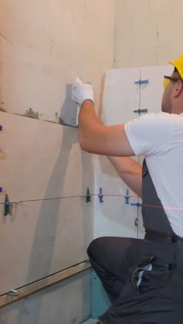 male craftsman installing ceramic tiles on the wall closeup vertical video
